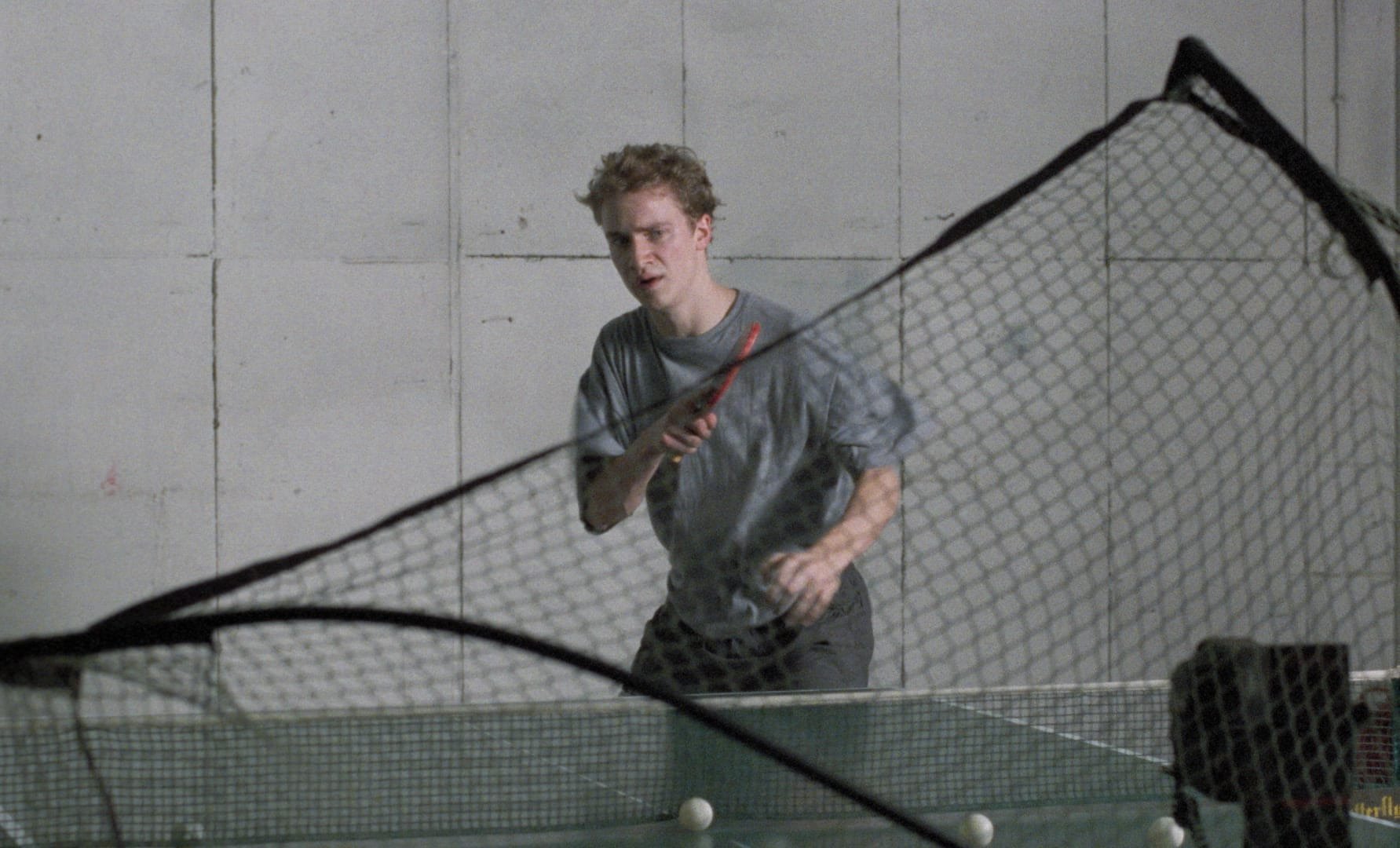 Still from the 1994 Michael Haneke film "71 Fragments of a Chronology of Chance" in which the young man practices table tenns